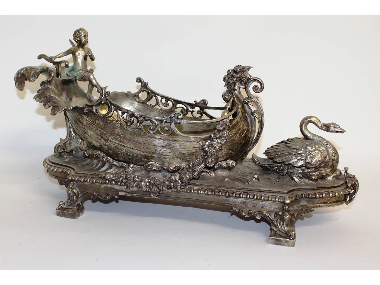 A good French plated centrepiece, a boat with cupid and swan, on a scrolled base. 21ins long.