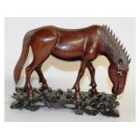 A Chinese carved wood horse on a stand. 11ins long.