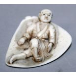 AN UNUSUAL EARLY 20TH CENTURY SIGNED JAPANESE IVORY NETSUKE, of a man lying on a triangular leaf,