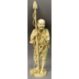 A LARGE SIGNED JAPANESE MEIJI IVORY FIGURE OF A FISHERMAN, standing in a grass skirt and holding a
