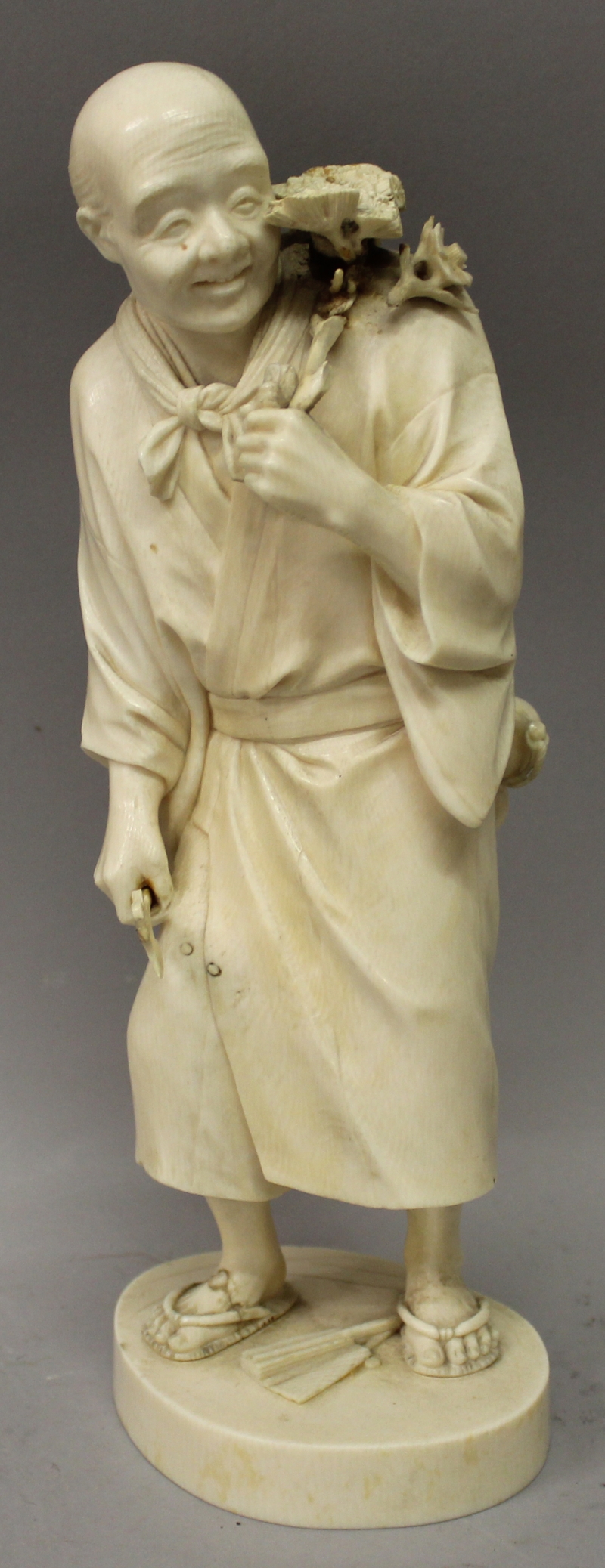 A LARGE GOOD QUALITY JAPANESE MEIJI PERIOD TOKYO SCHOOL IVORY OKIMONO OF A STANDING MAN, holding