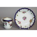 AN 18TH CENTURY WORCESTER CUP AND SAUCER painted with flowers under a blue border.
