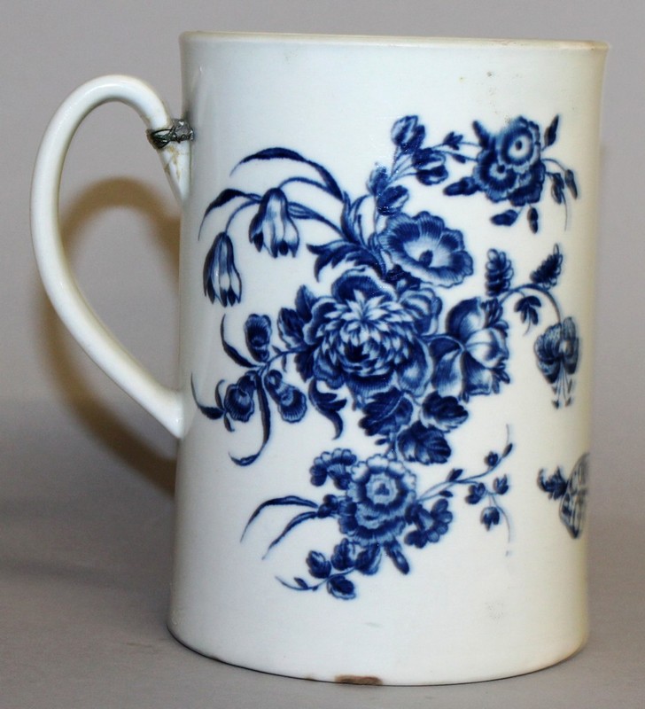 AN 18TH CENTURY WORCESTER MUG decorated both sides with flowers in under-glaze blue.