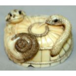 AN UNUSUAL EARLY 20TH CENTURY SIGNED JAPANESE IVORY NETSUKE, of a snake, toad and a snail, on top of