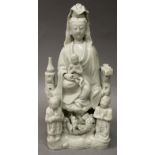 A CHINESE KANGXI PERIOD BLANC-DE-CHINE PORCELAIN FIGURE OF GUANYIN, seated on rockwork and holding