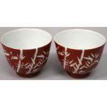 A PAIR OF CHINESE CORAL GROUND PORCELAIN CUPS, each decorated in white reserve with bamboo, each