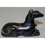 A SMALL CHINESE BRONZE MODEL OF A SEATED HOUND, with slightly silvered patination, 2.8in long.