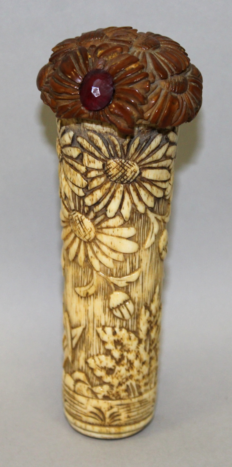 AN EARLY 20TH CENTURY ORIENTAL CARVED BONE CANE HANDLE, with a carved wood and glass inset pommel,