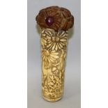 AN EARLY 20TH CENTURY ORIENTAL CARVED BONE CANE HANDLE, with a carved wood and glass inset pommel,
