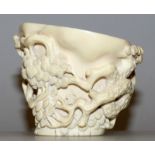 A GOOD 19TH CENTURY CHINESE CARVED IVORY LIBATION CUP, the sides decorated in high relief with