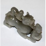 A CHINESE WHITE JADE-LIKE MODEL, in the form of two boys in the company of a dragon-like mythical
