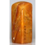 A CHINESE STONE SEAL, of amber tone, decorated in low relief with calligraphy and with sages in a