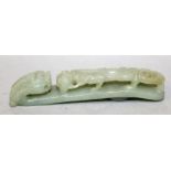 A CHINESE CELADON JADE BELT HOOK, the stem pierced and carved in high relief with a sinuous chilong,