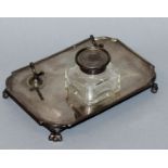 A RECTANGULAR INKSTAND with square cut glass bottle, on four paw feet, 6.75ins long. Maker: SEARLE &