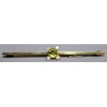 A PERIDOT AND PEARL BAR BROOCH in yellow gold.