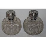 A GOOD PAIR OF CUT GLASS CIRCULAR SCENT BOTTLES with silver tops. 4ins high. Birmingham 1926.