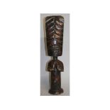 AN AFRICAN CARVED WOOD FEMALE FIGURE, hands holding her breast, with large rectangular head. 21ins