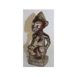 A YORUBA CARVED WOOD FEATHERS FIGURE, a woman holding a baby. 7ins high.