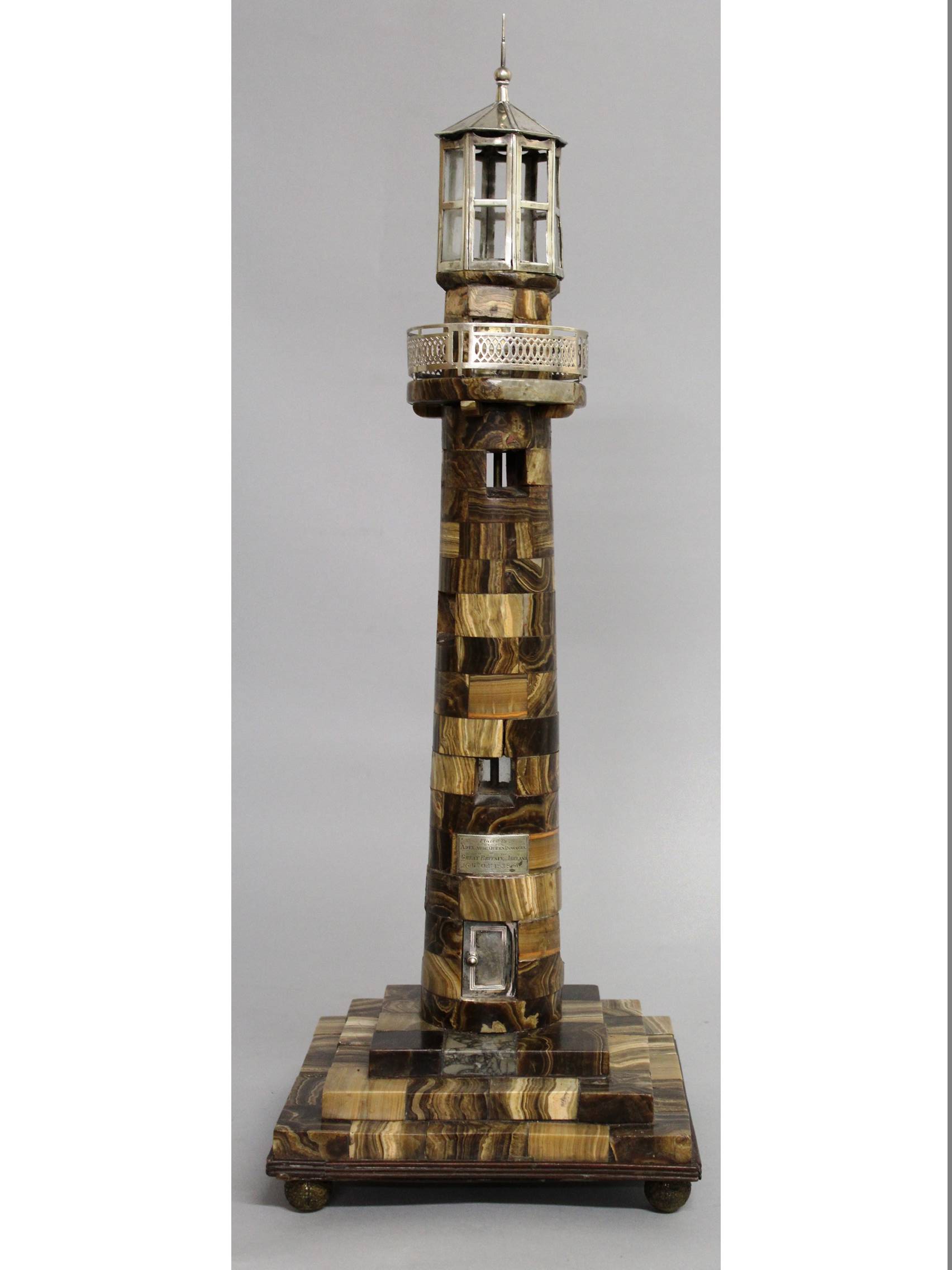 AN AGATE AND WHITE METAL MOUNTED MODEL OF A LIGHTHOUSE, the hexagonal top with canted cupola above a