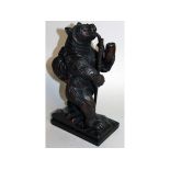 A "BLACK FOREST" CARVED WOOD SEATED BEAR smoking a pipe. 12ins high.