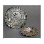 A PIERCED CIRCULAR BONBON DISH, repousse with a cupid and a small dish (2).