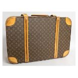 A LOUIS VUITTON SUITCASE with label. 26ins long, 9ins deep, 18ins wide.