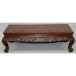 AN ORIENTAL CARVED HARDWOOD LOW RECTANGULAR TABLE, the frieze carved with dragons amidst cloud