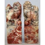 A PAIR OF EARLY 20TH CENTURY SOAPSTONE SEAL TYPE CARVINGS OF BUDDHISTIC LIONS, each seated on top of