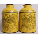 A PAIR OF YELLOW TOLEWARE TINS AND COVERS, decorated with birds and flowers in a garden setting.