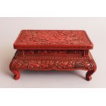 A JAPANESE MEIJI PERIOD RED CINNABAR LACQUER RECTANGULAR STAND, decorated in carved relief with
