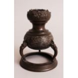 A JAPANESE MEIJI PERIOD BRONZE TRIPOD CANDLESTICK, the sides cast with wave decoration beneath