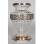 A CONTINENTAL SILVER AND CUT GLASS VASE of faceted baluster form, with mounted rim, floral cast