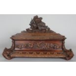 A GOOD 19TH CENTURY BLACK FOREST CARVED WOOD CASKET, the top with a deer being attacked by a dog,