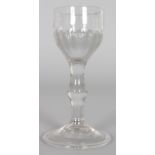 AN 18TH CENTURY BALUSTER WINE GLASS WITH HALF RIBBED BOWL, central knop on the stem with folded