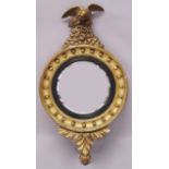 A REGENCY GILT FRAMED CONVEX MIRROR, surmounted by an eagle. 2ft 9ins high