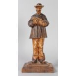 A RARE 19TH CENTURY BLACK FOREST CARVED AND PAINTED STANDING FIGURE OF A MAN, carrying a pig in