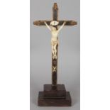 A 17TH CENTURY CARVED IVORY CORPUS CHRISTI, on a wooden cross. 20ins high.