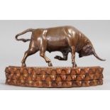 A BRONZE BULL, on a wooden base. 5ins long.