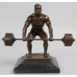 A BRONZE OF A WEIGHT LIFTER, on a square marble base. 9.5ins high.