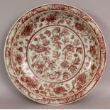 A LARGE CHINESE YUAN STYLE COPPER RED PORCELAIN DISH, decorated with scrolling leaf-stemmed peony