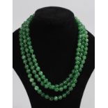 A LONG GREEN JADE NECKLACE.