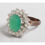 A GOOD LARGE EMERALD AND DIAMOND OVAL CLUSTER RING with large central emerald surrounded by fourteen