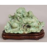 AN EARLY 20TH CENTURY CHINESE LIGHT GREEN CARVED HARDSTONE MODEL OF A BUDDHISTIC LION & PUPS,