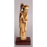 A SMALL EARLY 20TH CENTURY STAINED IVORY FIGURE OF A STANDING IMMORTAL, together with a fixed wood