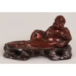 AN EARLY 20TH CENTURY CHINESE CARVED HARDWOOD FIGURE OF A RECLINING BUDAI, together with a fitted