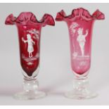 A PAIR OF MARY GREGORY RUBY VASES painted with a boy and girl. 12ins high.