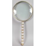 A LARGE MAGNIFYING GLASS with mother-of-pearl handle.