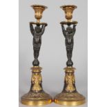 A GOOD PAIR OF EMPIRE BRONZE AND GILT CIRCULAR CANDLESTICKS with winged cupid supports, on