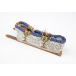 A miniature beaded cradle board with Skookum doll