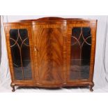 An early 20th Century mahogany display cabinet with bowed central cupboard flanked by glazed